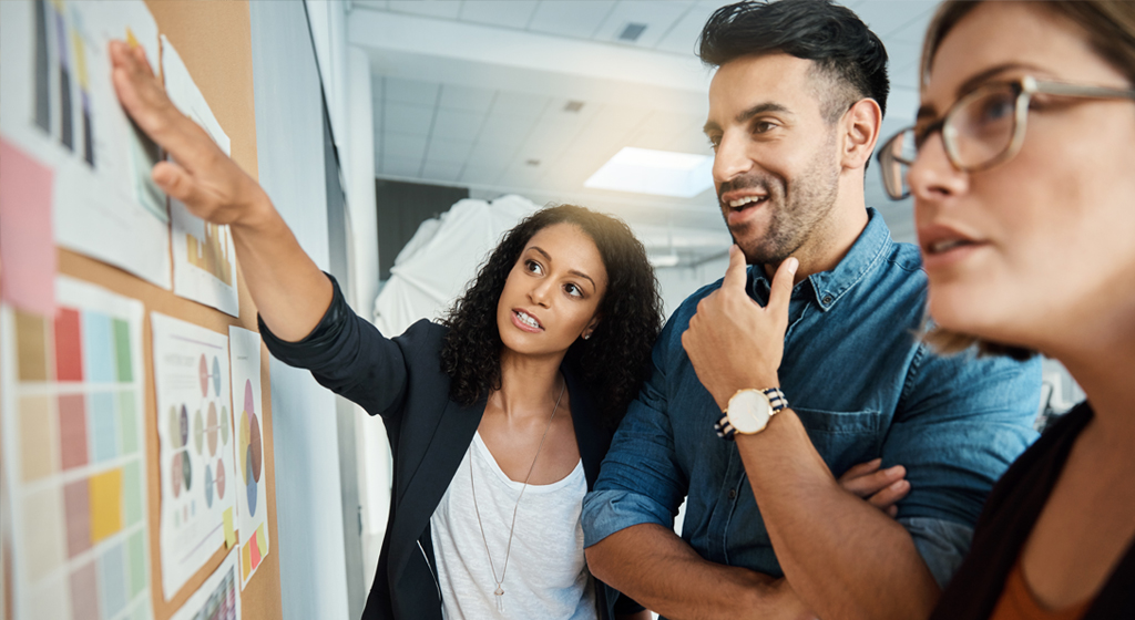 three people reviewing a board with charts and graphs