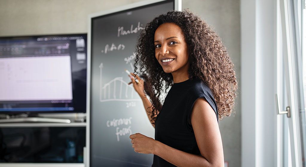 women standing in front of chalkboard.