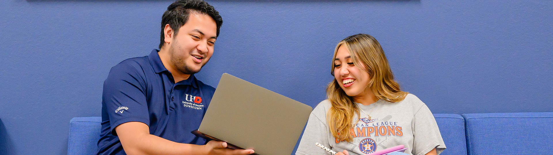 A male student showing something on his laptop to another student