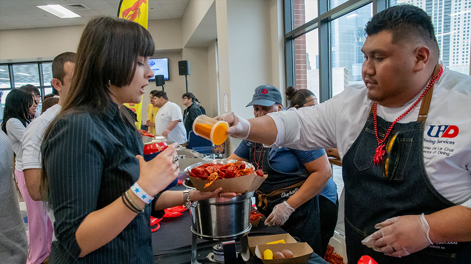 Staff pouring seasoning to student food