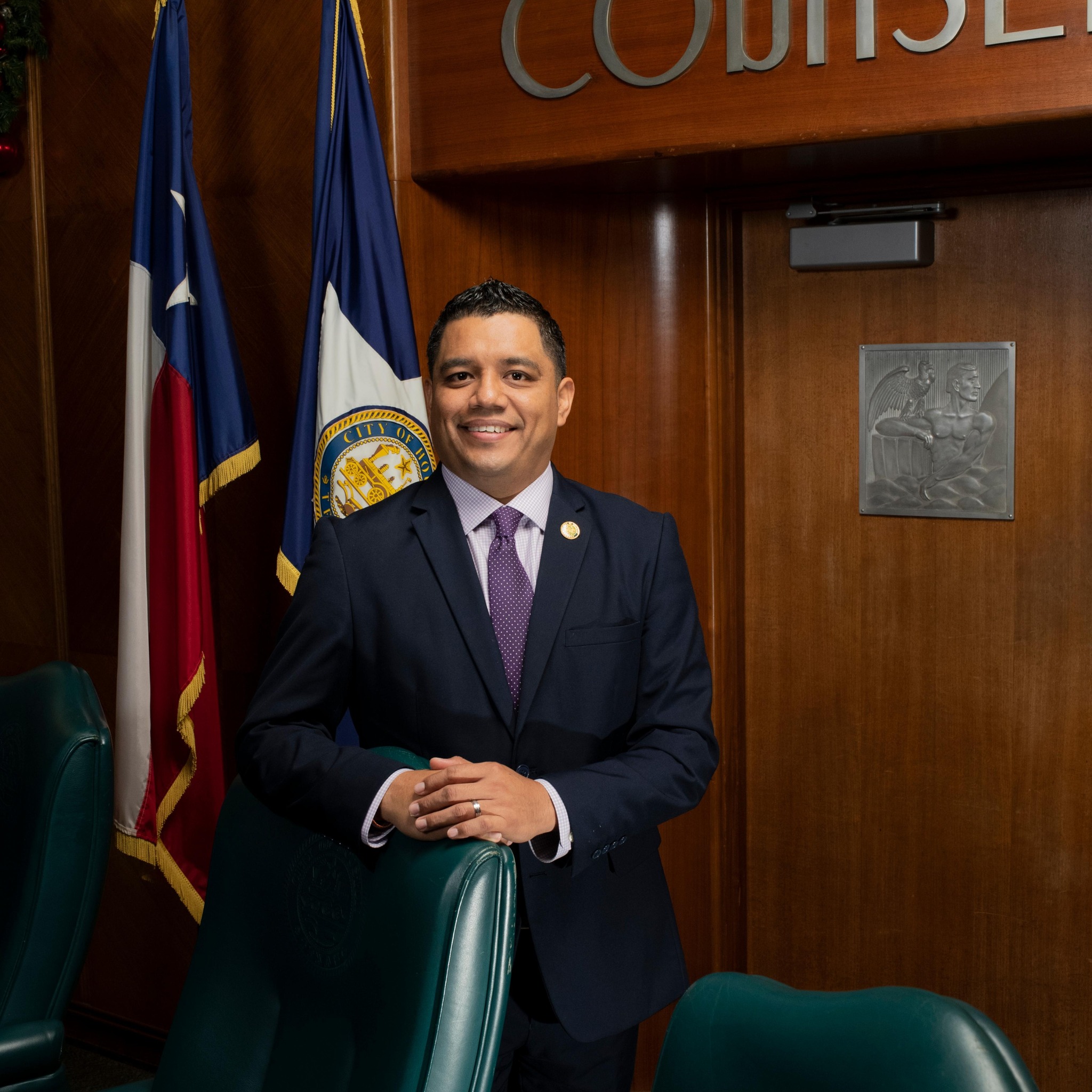 Photo of Joaquin Martinez in Houston City Council chambers. He is standing, wearing a suit and tie.