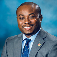 John Atasie, university of houston-downtown alum, seasoned global supply management professional, wears a suit and smiles