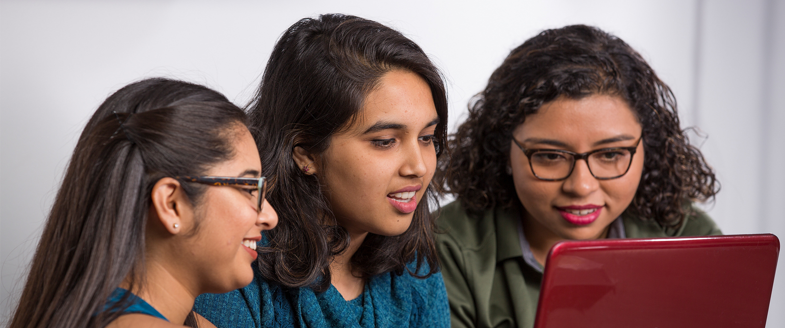 Three UHD students sharing a laptop