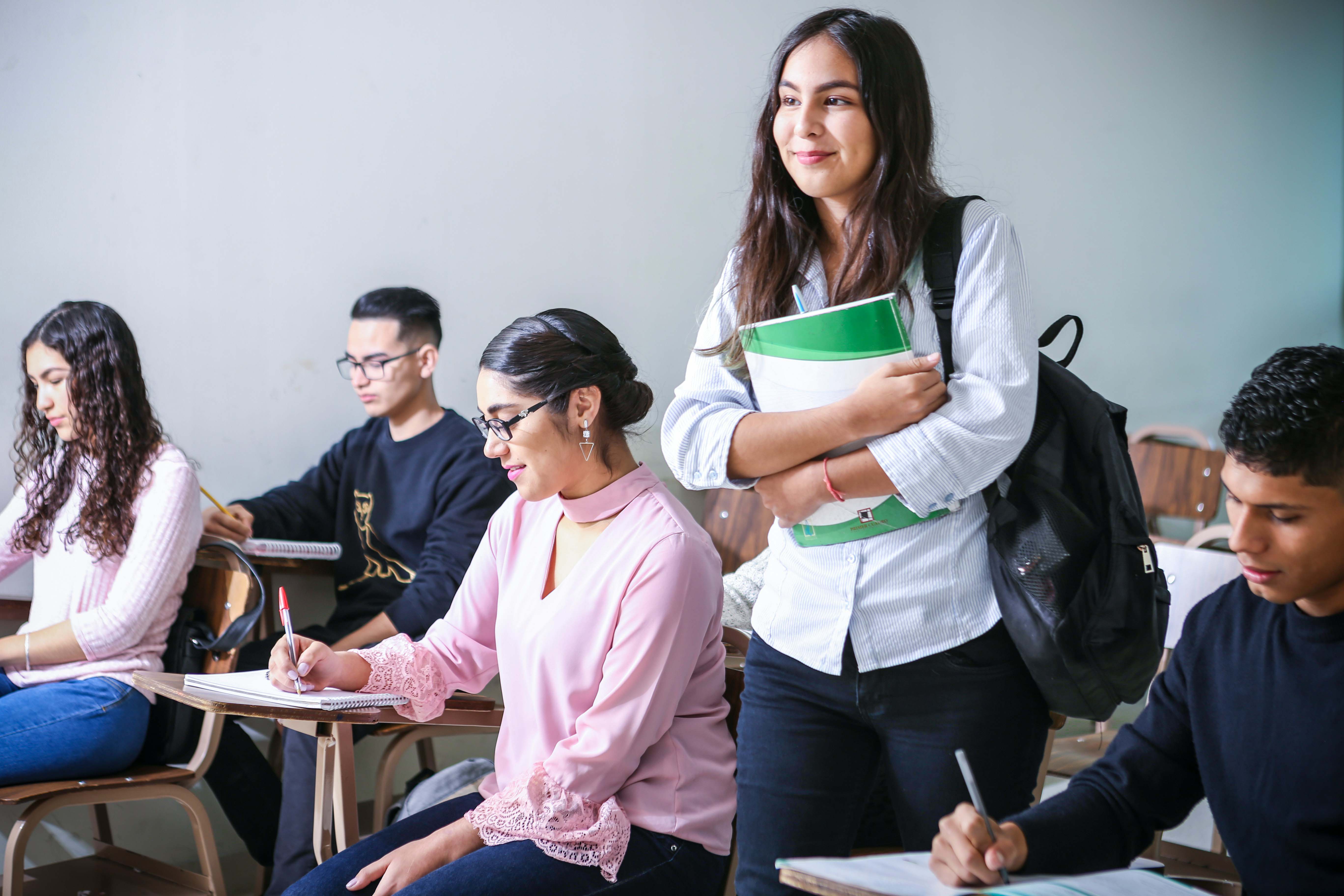 Student standing in class while other students taking a test.