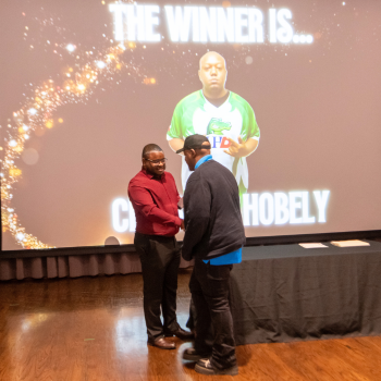 Uhd student shakes hands with a staff member while receiving a sports and fitness award 