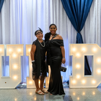 A UHD student dressed in formal wear stands aside an older adult in formal wear at UHD's One Main Event 