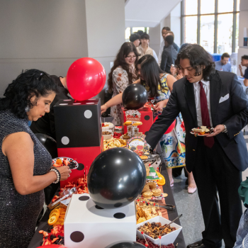 Students and staff at a table set with casino themed decorations and snacks at uhd's student awards in the skyline lounge