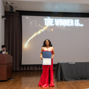 uhd student in red gown holds an award during uhd's student awards ceremony