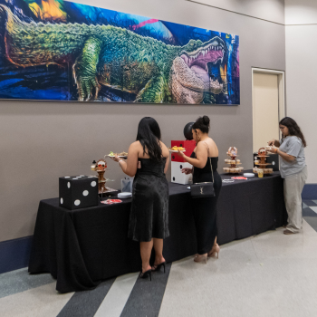 three uhd students at a buffet table with food and snacks