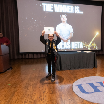 A UHD student holds an awards certificate 