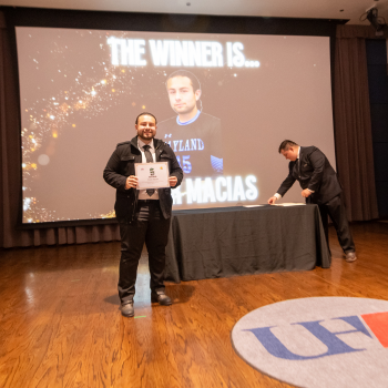 A UHD student holds an award certificate at the sports and fitness awards at UHD's One Main Event