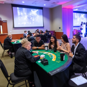 Students sit at a casino table in an event room at UHD