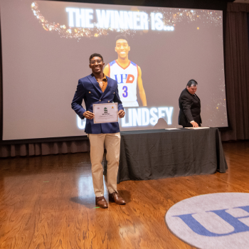 A UHD basketball player holds an awards certificate at the sports and fitness awards ceremony