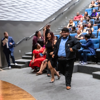 Two UHD students walk up to the stage to receive an award while the audience applauds